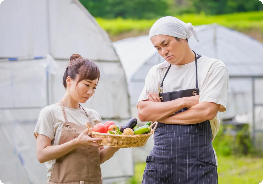 ハウスで作物を持つ農家の夫婦