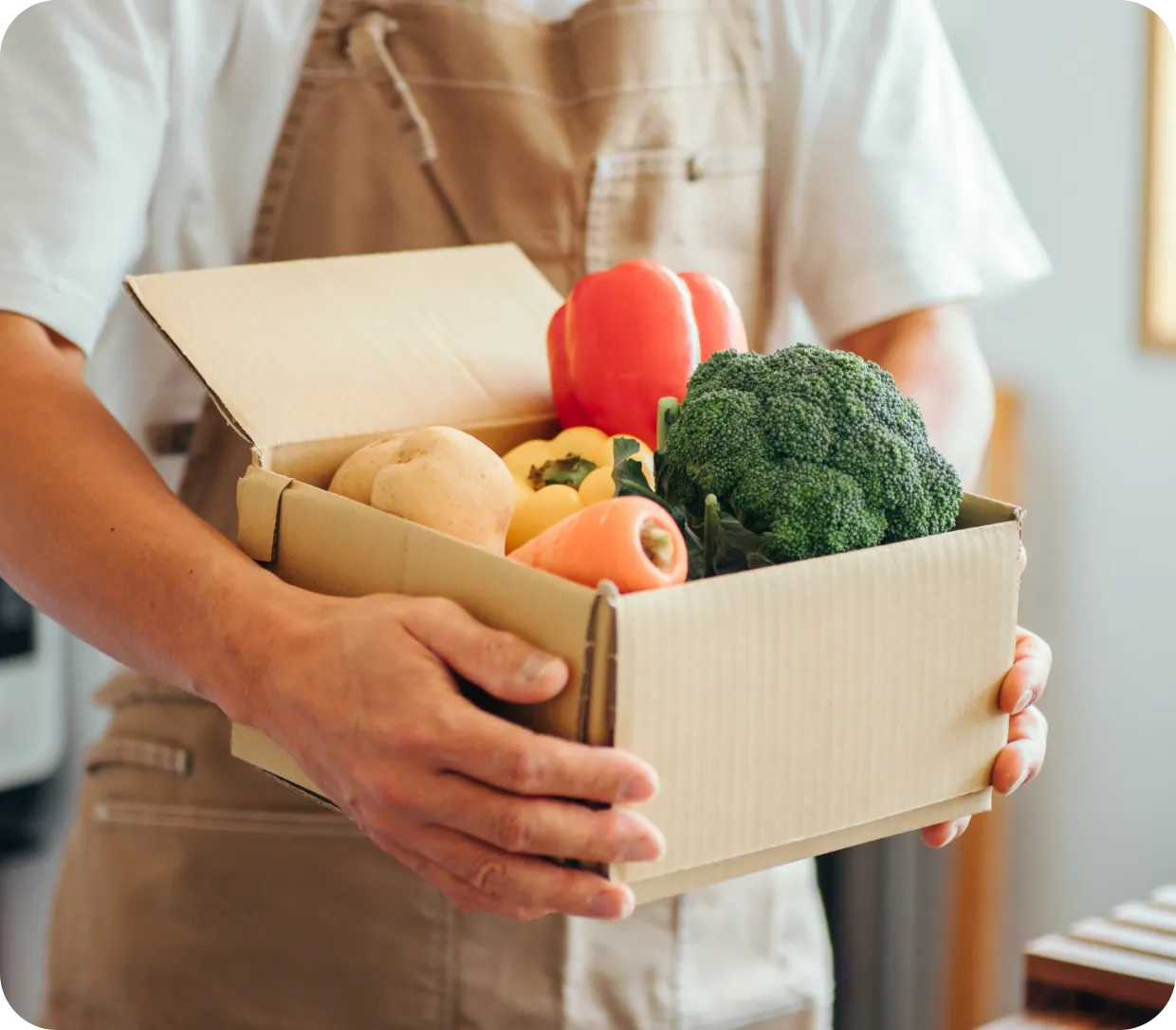 野菜の入った箱を持つ人